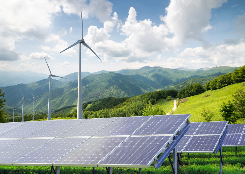 solar,panels,with,wind,turbines,against,mountanis,landscape,against,blue